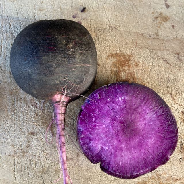 Un Radis d&#39;hiver Améthyste Noir Tourne-Sol posé sur une planche à découper en bois.