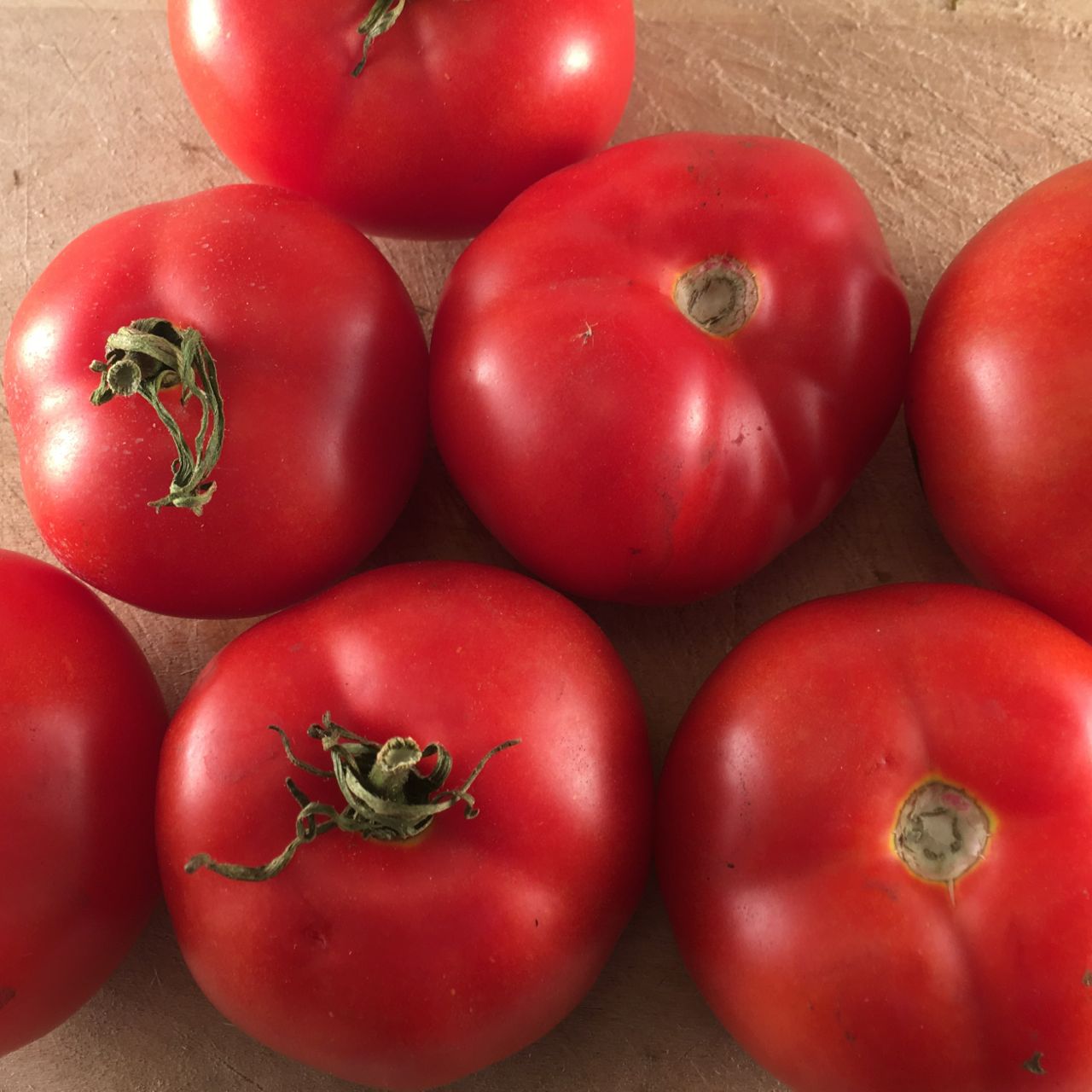 Un groupe de Tomate Rouge Québec #13, tendre avec un goût sucré sur une surface en bois. Marque : Tourne-Sol.