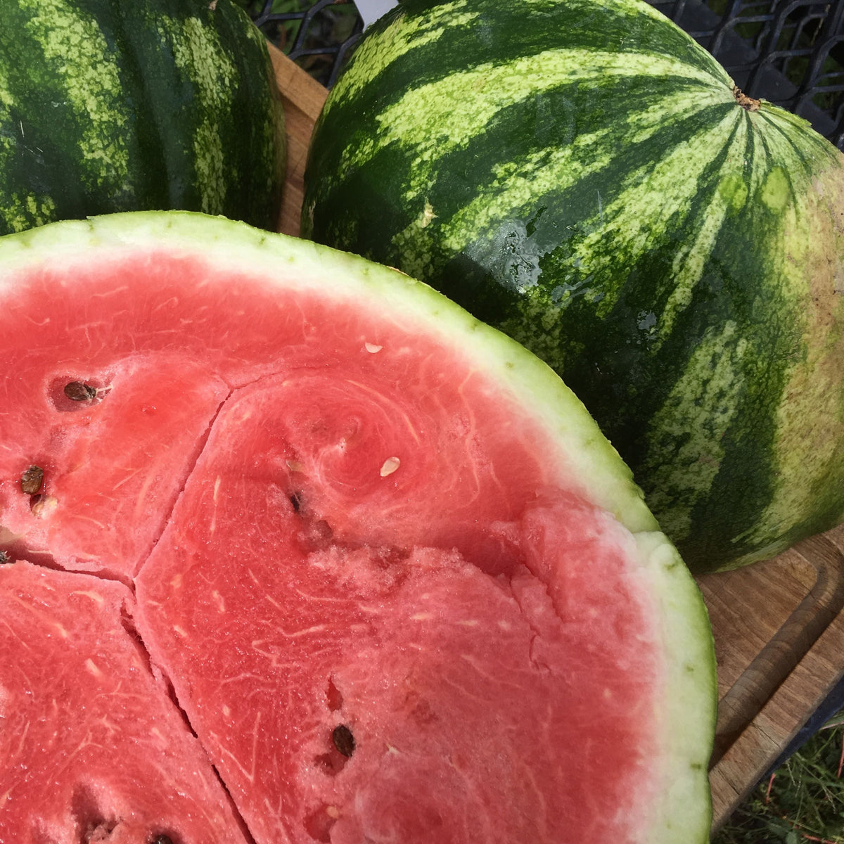 Une tranche de Melon d&#39;Eau Sweet Dakota Rose sur une planche à découper en bois.